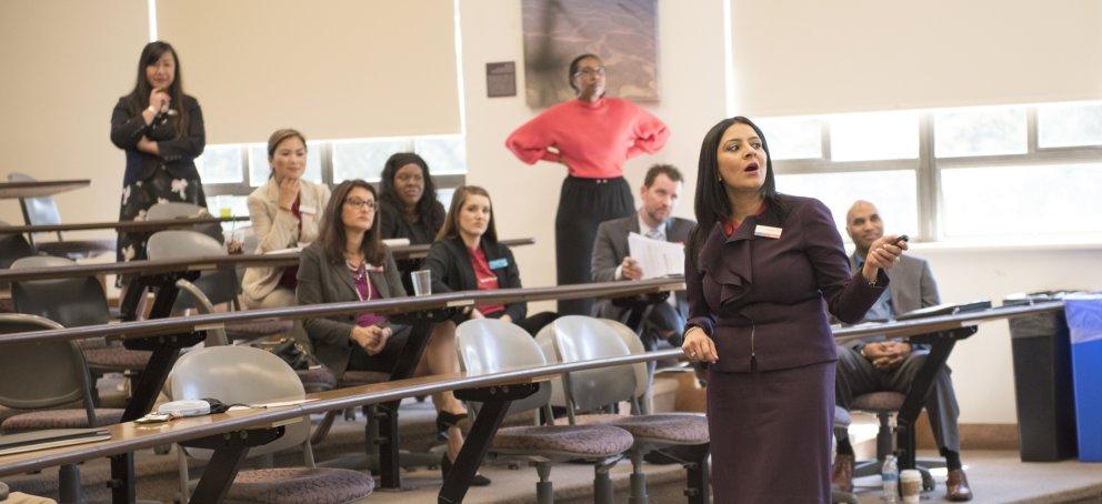 students sitting behind tables while a financial aid representative gestures to the white board